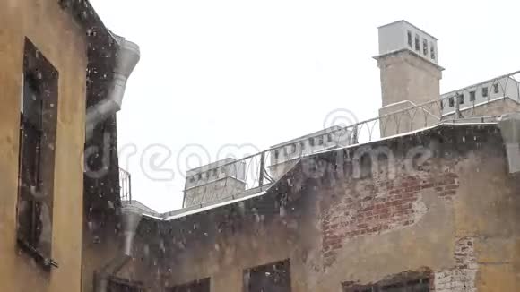 冬天大雪纷飞天空和一座有窗户的黄色老房子的屋顶视频的预览图