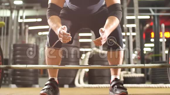 年轻的健美运动员准备在现代健身馆举起沉重的杠铃手握滑石粉视频的预览图