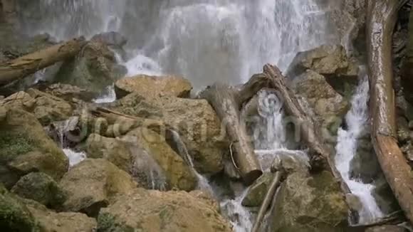 瀑布一股强大的水流顺着石头和原木流下来特写镜头潘视频的预览图