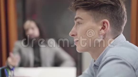 侧视特写的年轻白种人男子坐在与同事的桌子和讨论的想法有创意的团队视频的预览图