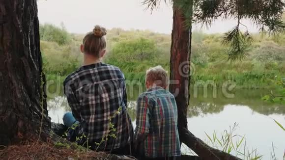 男孩和女孩坐在河边拥抱的后景视频的预览图