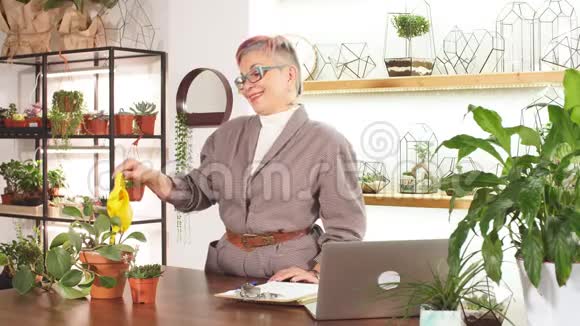 细心的高级女商人在办公室里给植物浇水视频的预览图