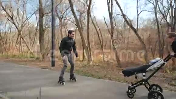 快乐的父母带着婴儿车和溜冰鞋在舒适的城市公园我的父亲滑旱冰妈妈推着视频的预览图
