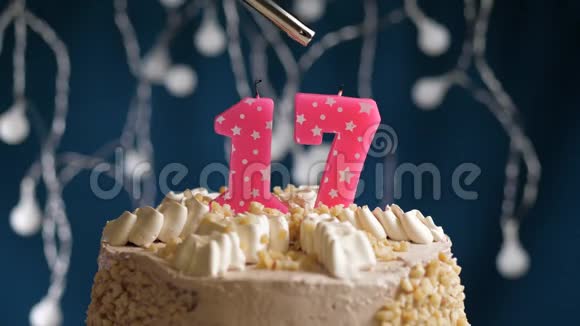 生日蛋糕有17个数字由较轻的粉红色蜡烛燃烧在蓝色的背景上蜡烛被点燃了慢动作视频的预览图