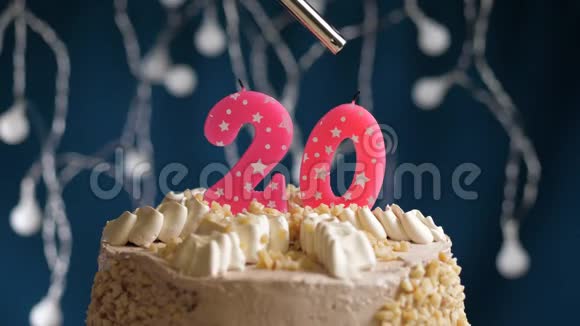 生日蛋糕有20个数字由较轻的粉红色蜡烛燃烧在蓝色的背景上蜡烛被点燃了慢动作视频的预览图