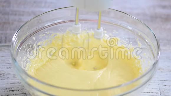 家庭主妇用搅拌机在碗里搅拌面团视频的预览图