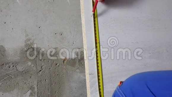那人用卷尺测量木板上的距离并作记号视频的预览图