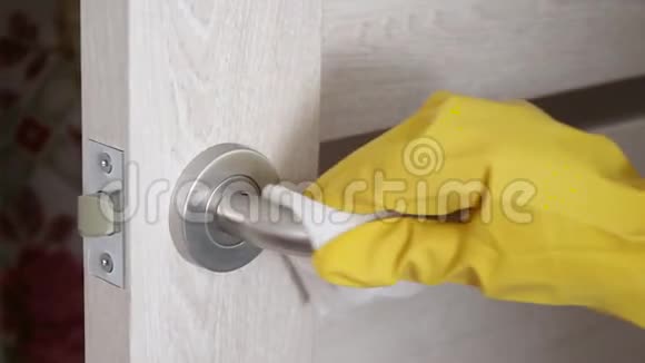 一个穿着黄色橡胶手套的人在一所房子一间办公室或一家医院里从细菌病毒和细菌中擦拭门把手视频的预览图