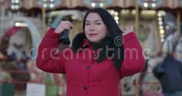 穿红色外套的成年白种人女人戴着头巾的肖像积极的成年女士站在市集等待视频的预览图
