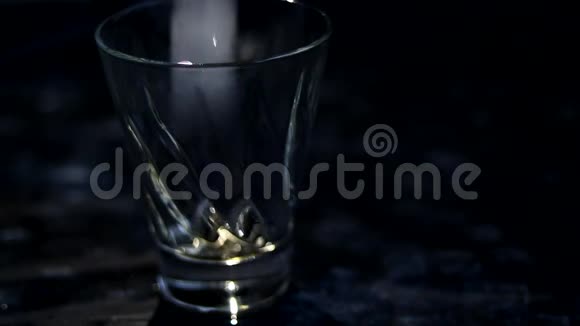 冰倒在黑暗背景上的透明玻璃中然后将棕色苏打水和柠檬水倒入同一个地方视频的预览图