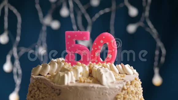生日蛋糕有50个数字由较轻的粉红色蜡烛燃烧在蓝色的背景上蜡烛被点燃了慢动作视频的预览图