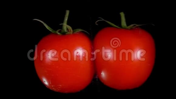 两个成熟的红西红柿在黑色的背景上飞舞碰撞着视频的预览图
