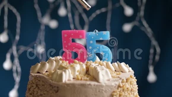 生日蛋糕有55个数字由较轻的粉红色蜡烛燃烧在蓝色的背景上蜡烛被点燃了慢动作视频的预览图