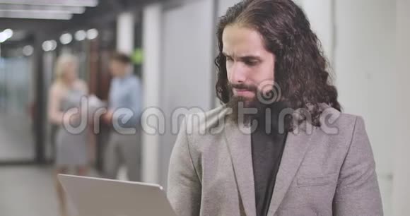 特写中东年轻人在笔记本电脑键盘上打字看着相机微笑着自信的上班族视频的预览图