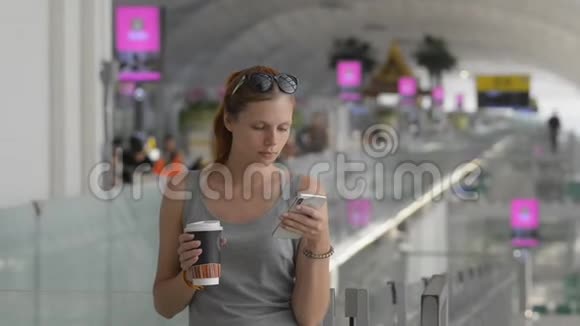 年轻女子使用智能手机和喝咖啡站在商场视频的预览图
