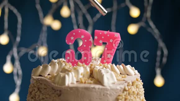 生日蛋糕37个数字燃烧由较轻的粉红色蜡烛在蓝色的背景蜡烛被点燃了慢动作视频的预览图