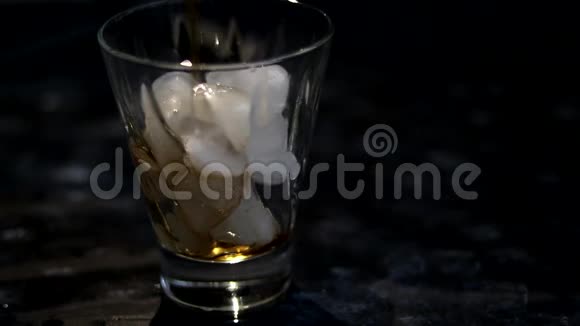 冰倒在黑暗背景上的透明玻璃中然后将棕色苏打水和柠檬水倒入同一个地方视频的预览图