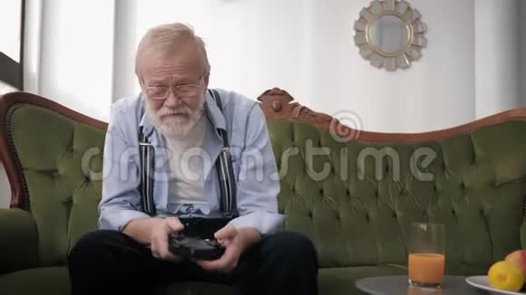 有魅力的老男人戴着眼镜手里拿着胡须和操纵杆玩电子游戏时玩得很开心视频的预览图