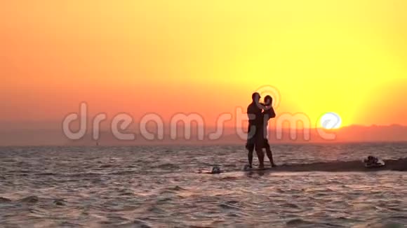 海滩上浪漫的日落情侣接吻剪影慢动作视频的预览图