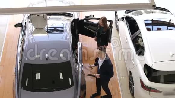 两个漂亮的女孩和一家汽车经销商的销售顾问交谈视频的预览图