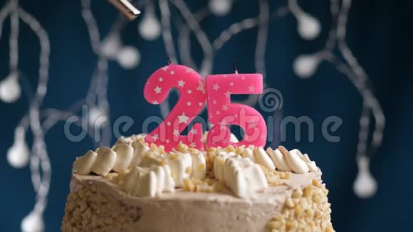 生日蛋糕有25个数字由较轻的粉红色蜡烛燃烧在蓝色的背景上蜡烛被点燃了慢动作视频的预览图