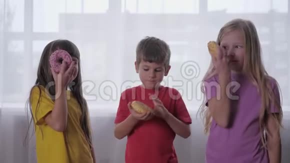 无忧无虑的童年快乐的孩子们一边看甜甜圈一边玩朋友聚会视频的预览图