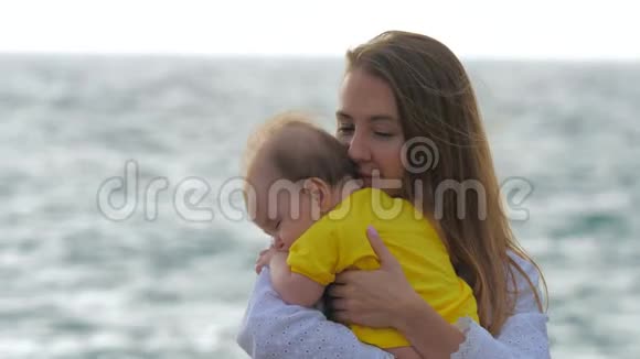 年轻的母亲在海边或海洋边抱着婴儿视频的预览图