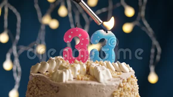生日蛋糕有33个数字由较轻的粉红色蜡烛燃烧在蓝色的背景上蜡烛被点燃了慢动作视频的预览图