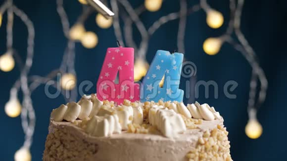 生日蛋糕有44个数字由较轻的粉红色蜡烛燃烧在蓝色的背景上蜡烛被点燃了慢动作视频的预览图
