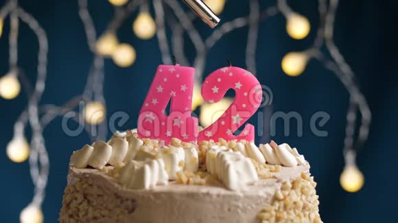 生日蛋糕42个数字燃烧由较轻的粉红色蜡烛在蓝色的背景蜡烛被点燃了慢动作视频的预览图