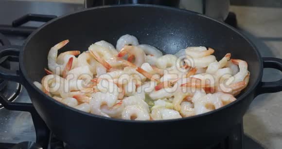 一个女人用辣椒和大蒜将炸虾搅入锅中视频的预览图