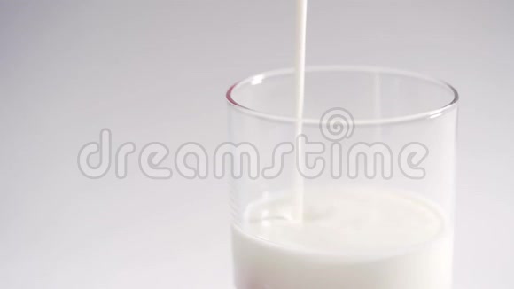 一个人将新鲜的有机酸奶倒入透明玻璃中牛奶酸奶慢慢地充满玻璃隔离在白色上视频的预览图