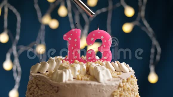 生日蛋糕有13个数字由较轻的粉红色蜡烛燃烧在蓝色的背景上蜡烛被点燃了慢动作视频的预览图