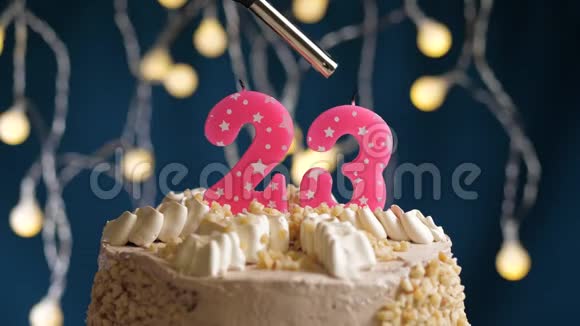 生日蛋糕有23个数字由较轻的粉红色蜡烛燃烧在蓝色的背景上蜡烛被点燃了慢动作视频的预览图