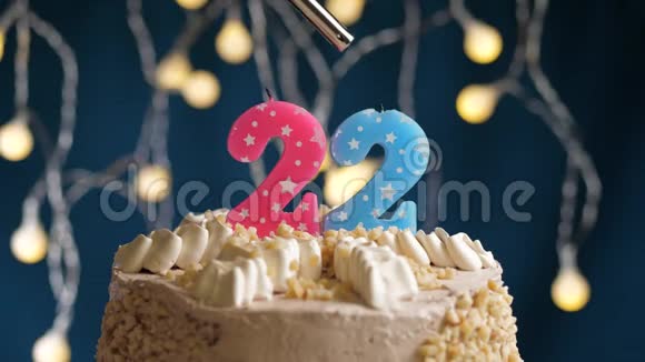 生日蛋糕有22个数字由较轻的粉红色蜡烛燃烧在蓝色的背景上蜡烛被点燃了慢动作视频的预览图