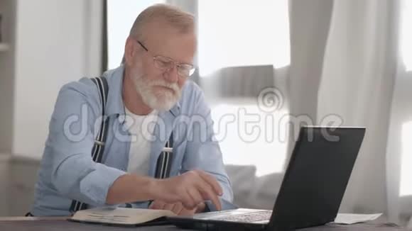 有魅力的老退休老人戴着眼镜在电脑上工作银行账户和在线支付微笑和微笑视频的预览图