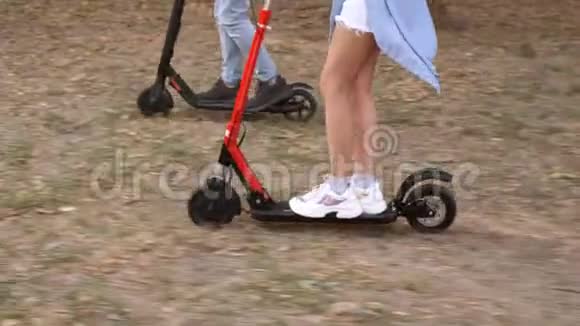 可爱的一对夫妇乘坐电动滑板车在草地的侧面观看视频的预览图