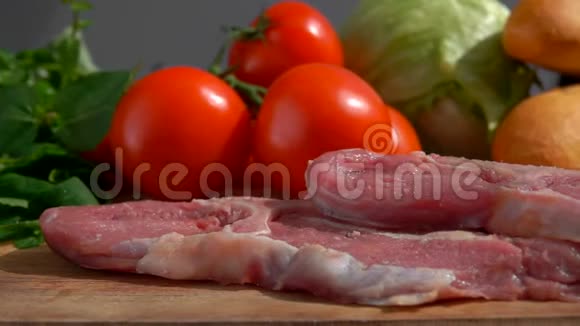 猪肉牛排正落在新鲜蔬菜背景上的木板上视频的预览图