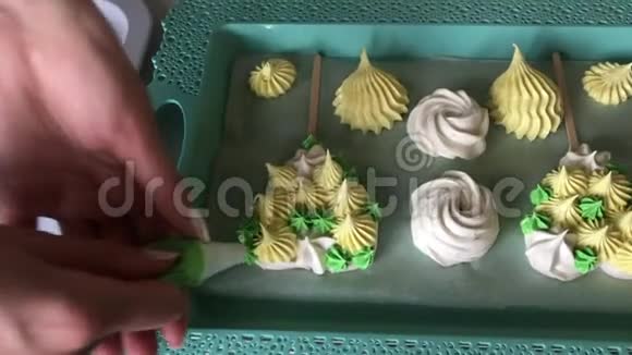 烹饪不同形状颜色和大小的棉花糖放在托盘上女人用糕点袋添加了棉花糖的元素视频的预览图