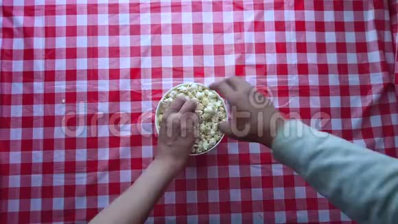 从碗里吃爆米花的人手的俯视图视频的预览图