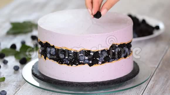 糖果师用蓝莓和黑莓装饰一个漂亮的蛋糕视频的预览图