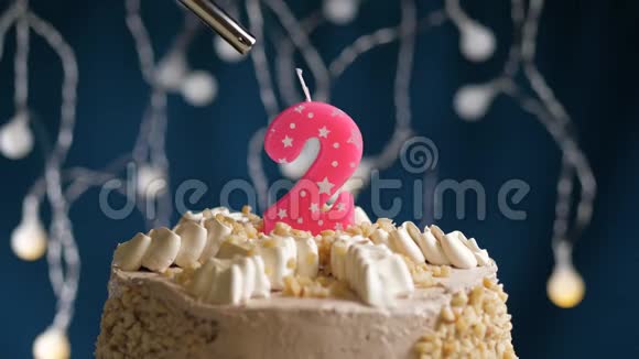 生日蛋糕有两个号码由较轻的粉红色蜡烛燃烧在蓝色的背景上蜡烛被点燃了慢动作和特写视频的预览图