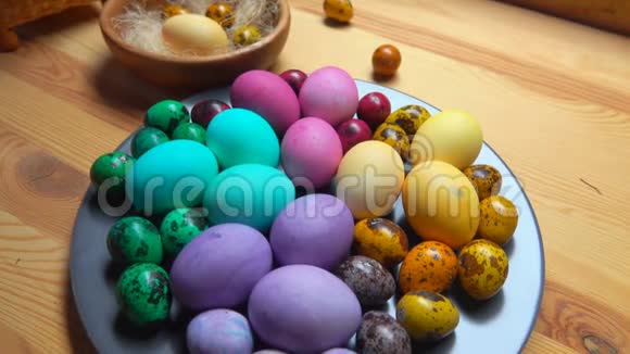 桌子上的灰色盘子上有多种颜色的复活节鸡和鹌鹑蛋视频的预览图