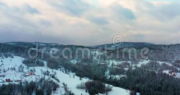 森林覆盖着积雪的鸟瞰图山上村庄的鸟瞰图视频的预览图
