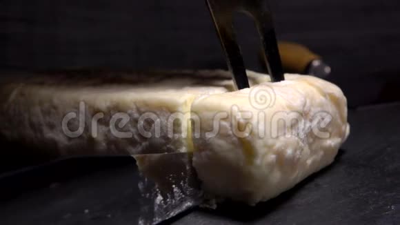 叉子从一块黑石板上举起一块柔软的山羊奶酪视频的预览图