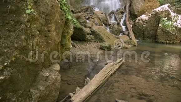 瀑布一股强大的水流顺着石头和原木流下来特写镜头潘视频的预览图