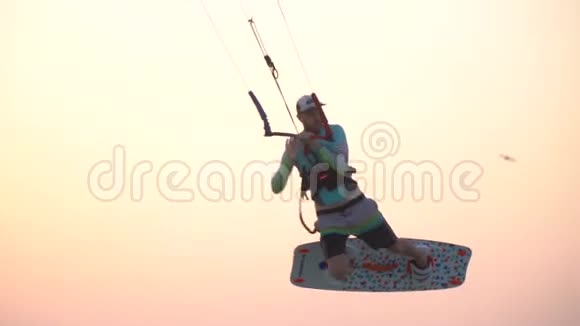 接近空中的风筝冲浪者飞行和做把戏五彩缤纷的日落视频的预览图