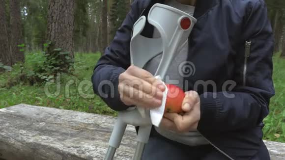 残疾女性拄着拐杖在公园里长椅上清洗苹果视频的预览图