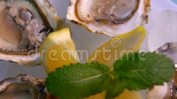 提供新鲜开放的美味牡蛎和柠檬的白色盘子的特写全景视频的预览图
