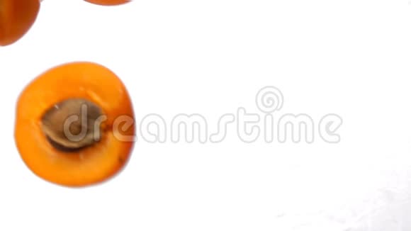 成熟多汁的杏半部分在白色背景上对角飞行视频的预览图